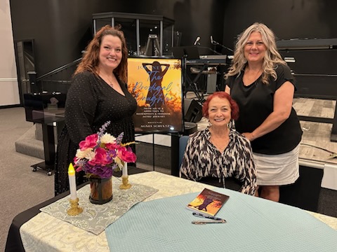 Agnes Schultz with supporters beside her book display